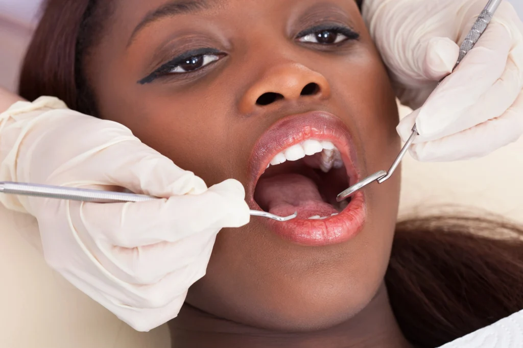 A close-up of a person's upper body with gloved hands performing a procedure using a dental instrument