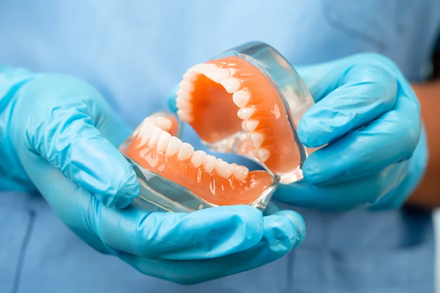 affordable dentures gastonia gloved hands holding upper and lower dentures