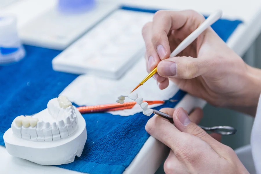 dentures in concord nc technician painting porcelain teeth in lab