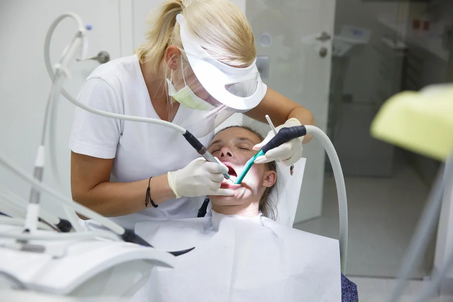 tooth extraction charlotte nc dental hygienist treating a patient with suction and handpiece (1)