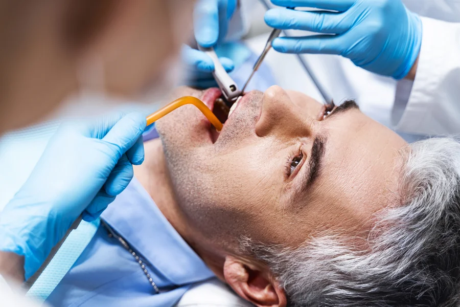 tooth extraction charlotte nc male patient receiving dental treatment with suction tube (1)